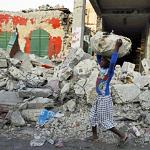 A girl balances a bundle on her head as she walks by collapsed buildings in earthquake torn Port-au-Prince, 10 Feb 2010