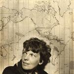 Amelia Earhart in front of a map of here proposed trip around he world