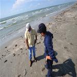 In this photo provided by the U.S. Coast Guard, Ronnie Rouse, of T&T Marine Salvage, a company contracted to clean tar balls off of Galveston beaches, left, and Petty Officer 3rd Class Andrew Garcia f