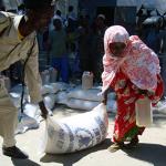 A Somali policeman helps a displaced Somali woman to carry food aid provided by a local NGO and the World Food Program in Mogadishu in May