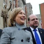 U.S. Secretary of State Hillary Rodham Clinton smiles in front of a statue of her husband former President Bill Clinton, in Pristina, Kosovo, 13 Oct. 2010