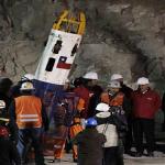 Chile's President Sebastian Pinera, far right, watches a rescue worker enter the Phoenix capsule to begin the rescue of the 33 trapped miners
