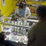 An employee, behind the counter, helps clients choose from jars at a medical marijuana dispensary in Los Angeles