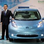 Nissan chief Carlos Ghosn stands next to a Nissan Leaf, a fully electric car