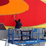 In this photograph taken on Friday, Aug. 14, 2009, Stephan Ackermann paints red on a mural by his brother the artist Franz Ackermann titled 