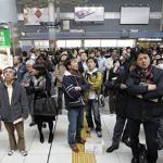 Train passengers wait at Tokyo's Shinagawa station after service was halted