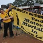 An Amnesty International member unfolds a banner as she prepares for the campaign against maternal deaths in Freetown, Sierra Leone (File Photo) 