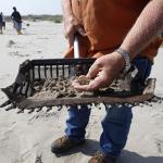 An Inspector displays oiled sand in a sifter as a cleanup crew works on Fourchon Beach in Port Fourchon, La