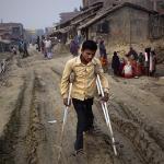 An unidentified polio-affected man walks on crutches in the village of Kosi in India