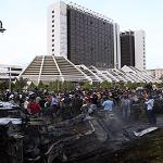 People stand near destroyed cars after an explosion at Tibesti hotel in Benghazi, Libya June 1, 2011